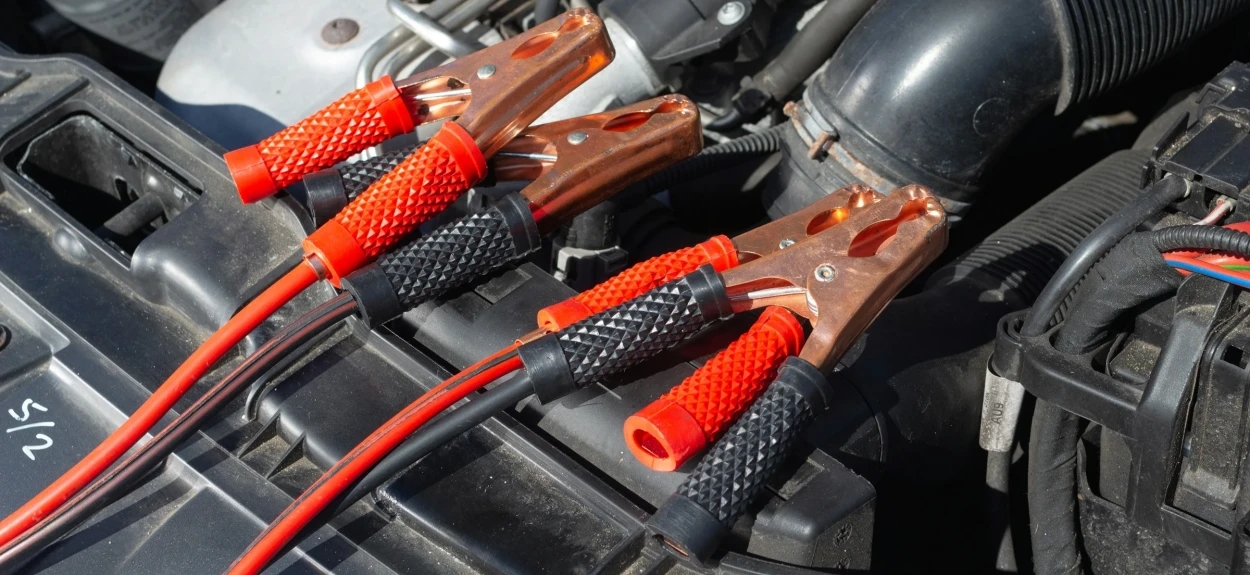 Crvene kleme startnih kablova spojene na akumulator automobila za paljenje motora