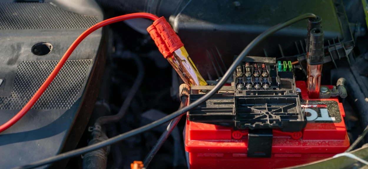 Prazan akumulator automobila sa priključenim kablovima za proveru i punjenje