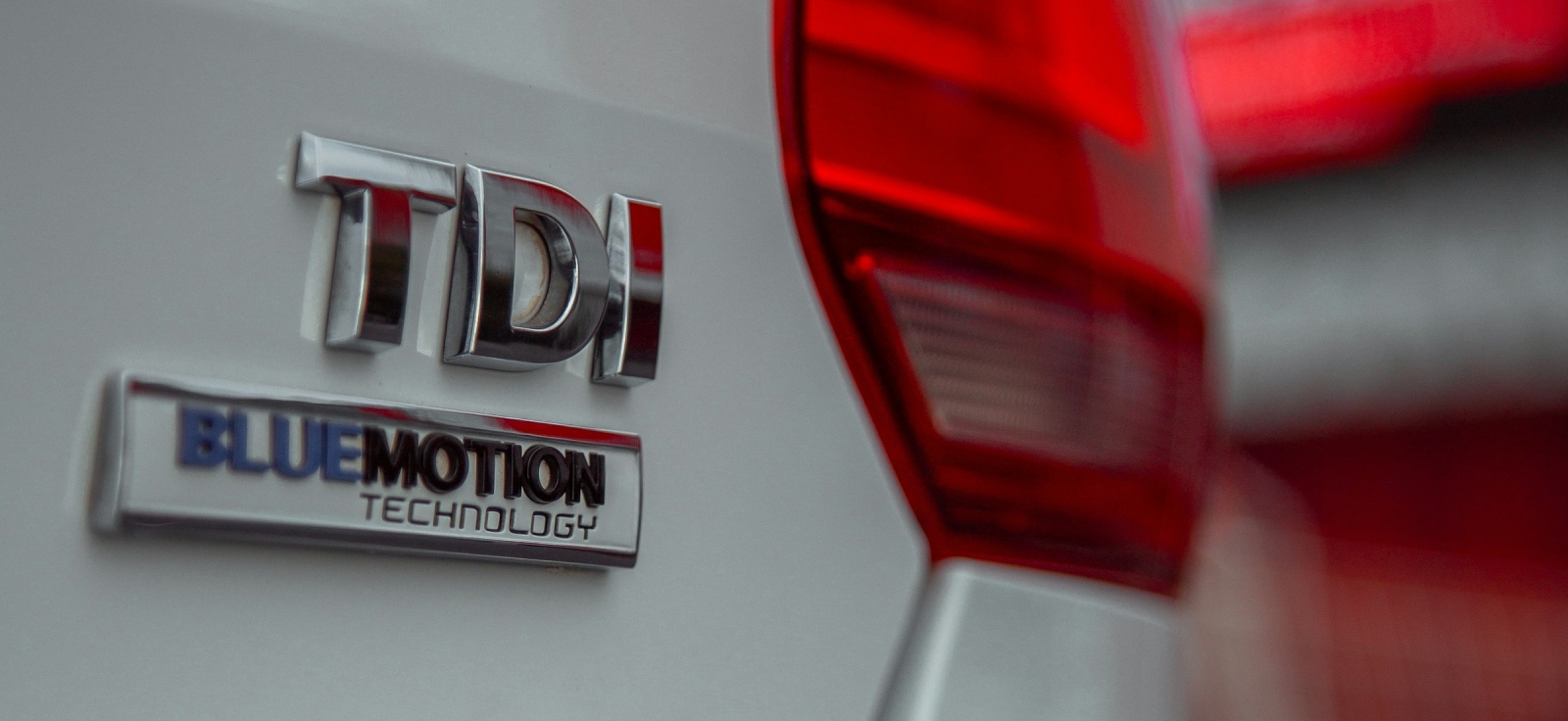 Detalj srebrnog VW automobila sa TDI i BlueMotion Technology hromiranom oznakom na prtljažniku