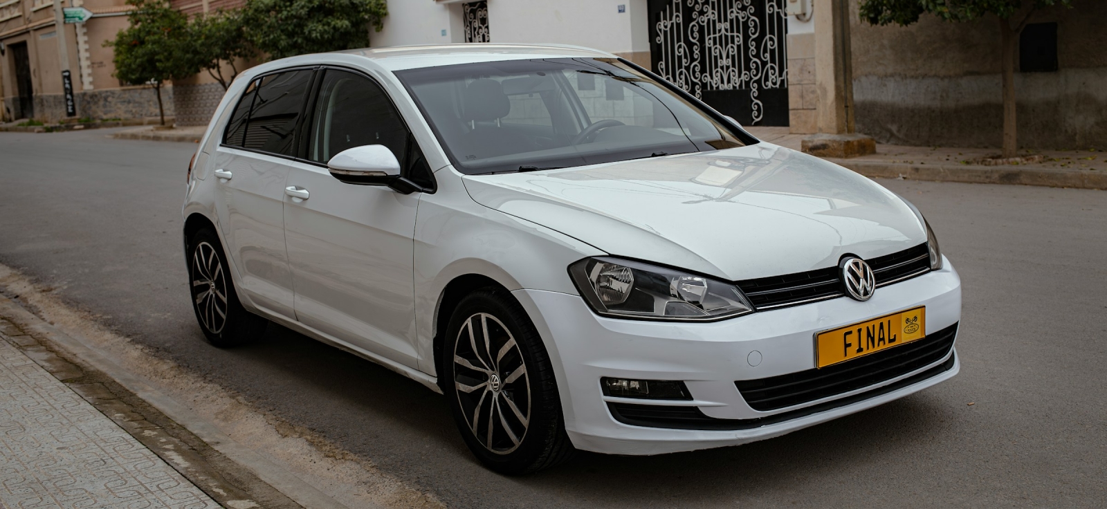 Beli Volkswagen Golf 7 parkiran na ulici koji prikazuje aerodinamičan dizajn i specifične felne BlueMotion serije