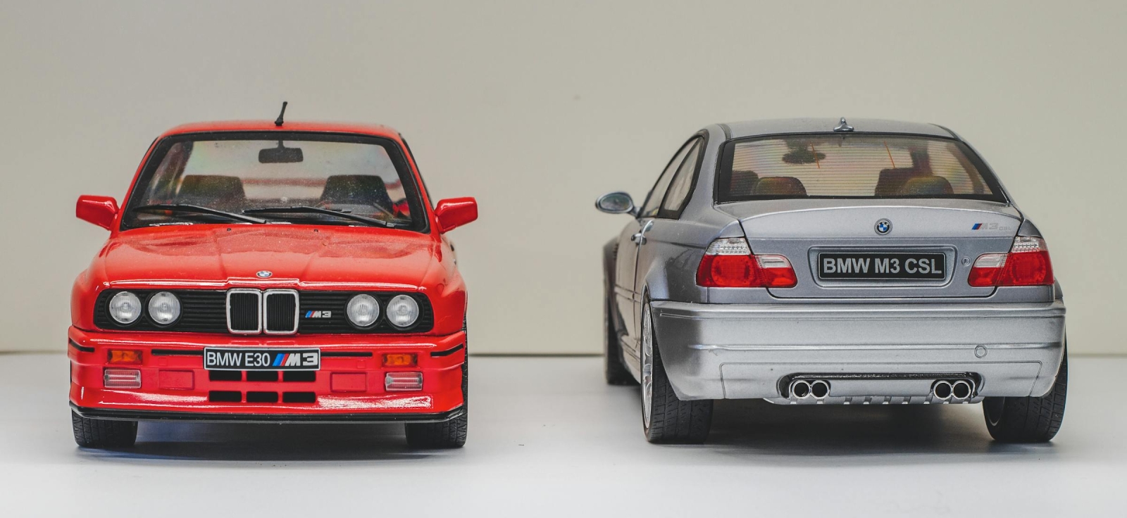 Crveni BMW M3 E30 i sivi BMW M3 E46 parkirani jedan pored drugog, prikazujući generacijsku evoluciju M3 serije