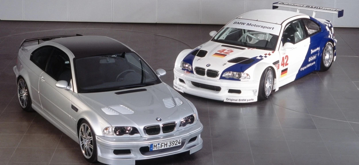 Srebrni BMW M3 GTR ulična verzija pored belog trkačkog BMW Motorsport modela sa brojem 42 u garaži