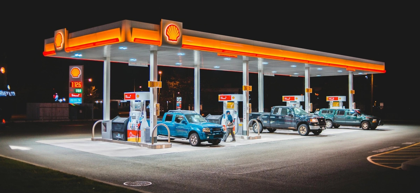 Shell benzinska pumpa noću sa automobilima koji toče premium gorivo, simbol kvaliteta goriva i razlika među brendovima