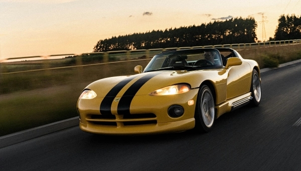 Žuti Dodge Viper RT/10 prve generacije sa prepoznatljivim crnim trkačkim trakama u vožnji tokom zalaska sunca