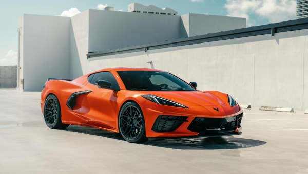 Narandžasta Chevrolet Corvette C8 sa središnjim motorom na parkingu, savremeni američki superautomobil koji ubrzava do stotke ispod 3 sekunde