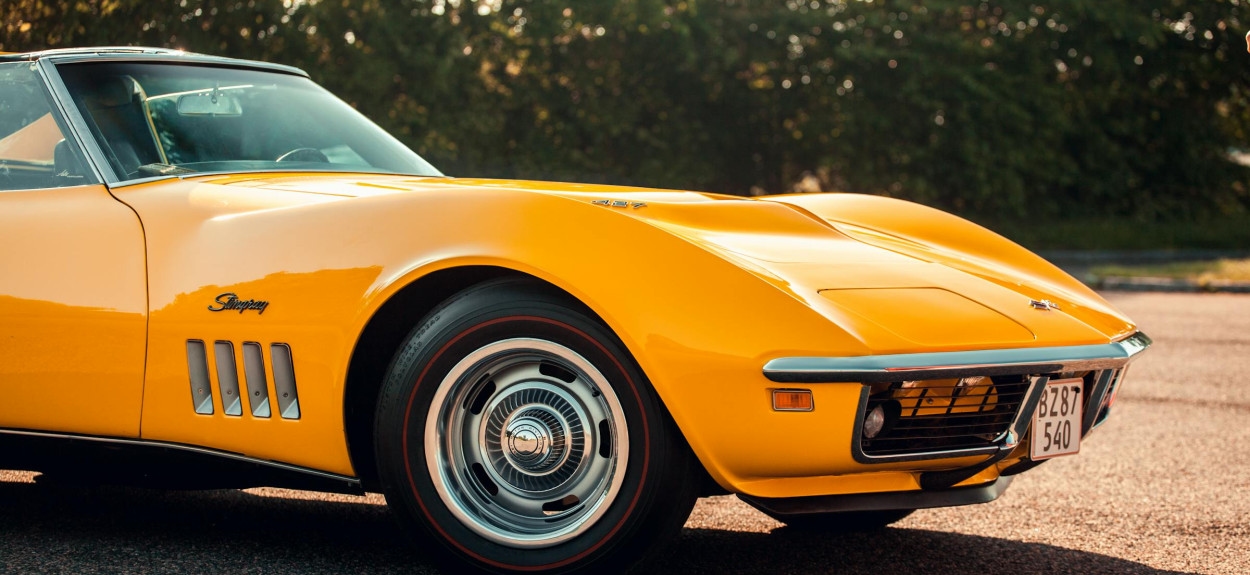 Zuta klasična Chevrolet Corvette Stingray iz zlatne ere dizajna, sa prepoznatljivim mišićavim linijama i hromiranim detaljima