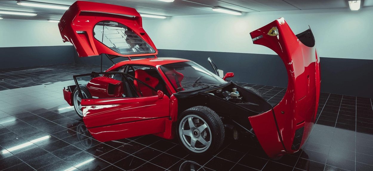 Ferrari F40 sa podignutim zadnjim poklopcem motora i otvorenim vratima, otkriva 2.9L V8 twin-turbo motor i ogoljenu konstrukciju od karbona i kevlara