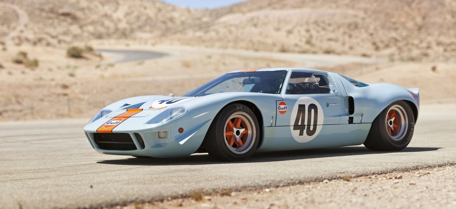 Klasični Ford GT40 Mk I u Gulf plavo-narandžastoj boji na trkačkoj stazi, legenda rivalstva Ford vs Ferrari i simbol pobede na Le Mansu