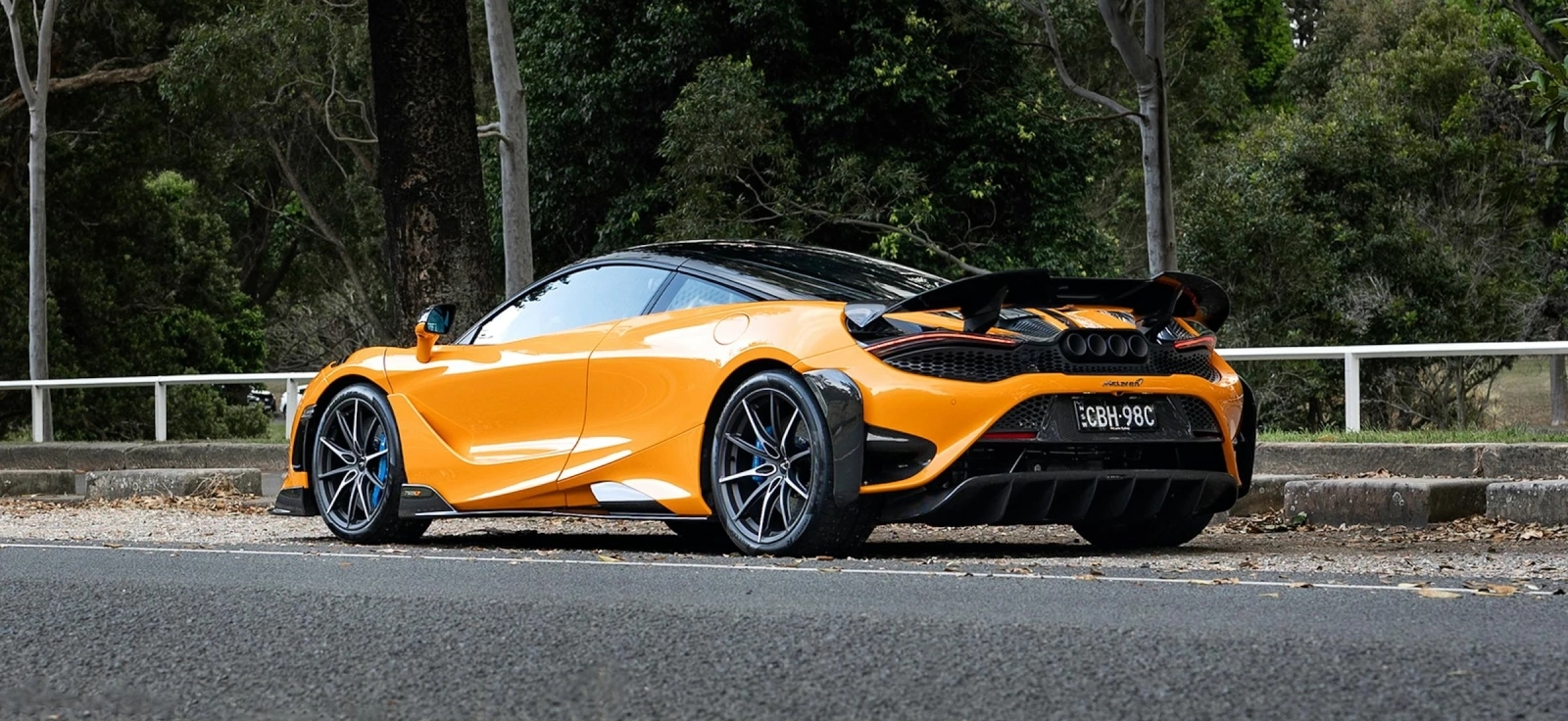 Automobil parkiran pored puta slikan od pozadi gde se vidi spojler koji se pomera.