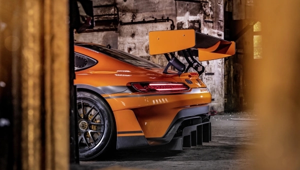 Narandzasti automobil marke Porsche parkiran u gazari prikaz spojlera.