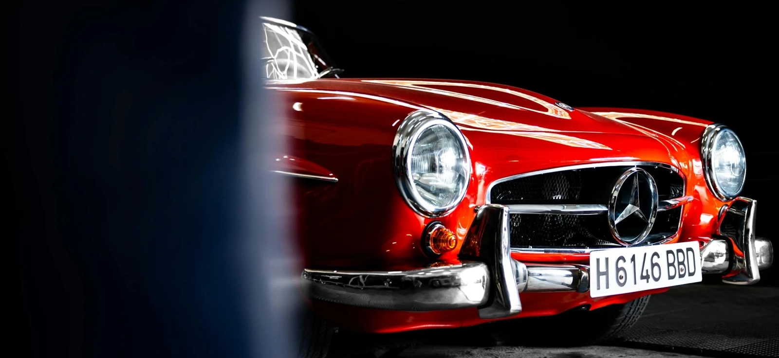 Prednji deo crvenog klasičnog Mercedesovog sportskog automobila, hromirani branik i retro dizajn iz zlatne ere brenda