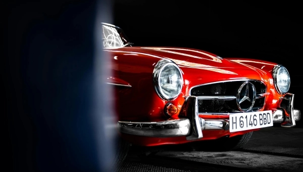 Prednji deo crvenog klasičnog Mercedesovog sportskog automobila, hromirani branik i retro dizajn iz zlatne ere brenda