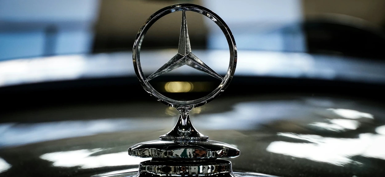 Detalj Mercedes-Benz znaka na haubi klasičnog automobila – trokraka zvezda kao simbol istorije i luksuza Mercedesa