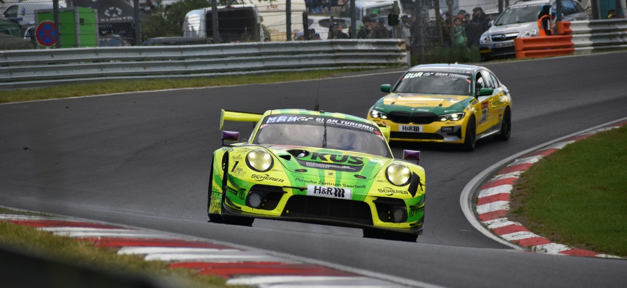 Zeleni Porsche 911 GT3 u oštroj krivini na stazi Nürburgring Nordschleife tokom trke.