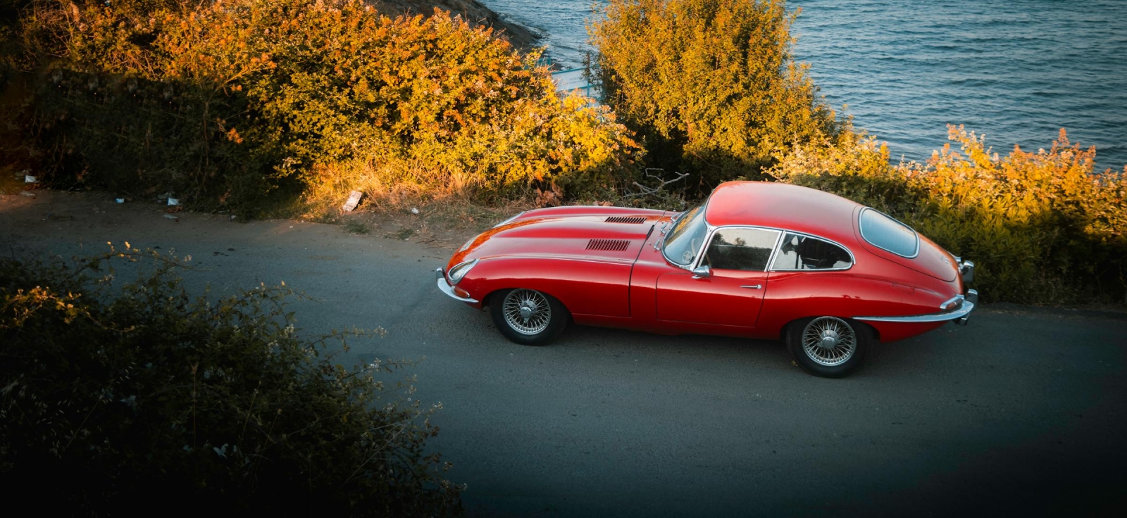 Kultni crveni sportski automobil Jaguar E-Type parkiran pored obale mora kao najlepsi auto na svetu
