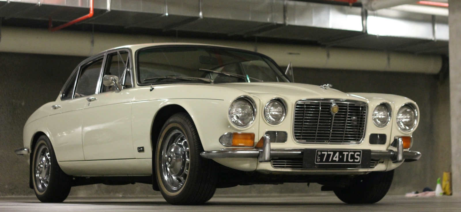 Klasicni beli Jaguar XJ limuzina parkiran u garazi kao simbol britanskog luksuza i aristokratije