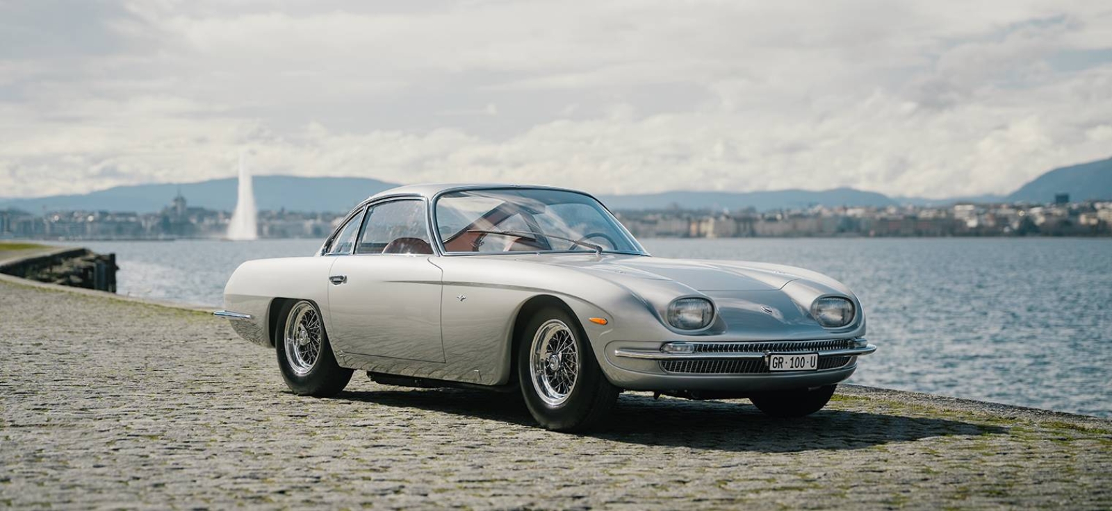 Srebrni Lamborghini 350 GT, prvi serijski model kompanije, parkiran pored jezera