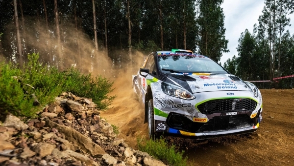 Savremeni reli automobil u brzoj vožnji kroz šumski put, podiže prašinu u zavoju