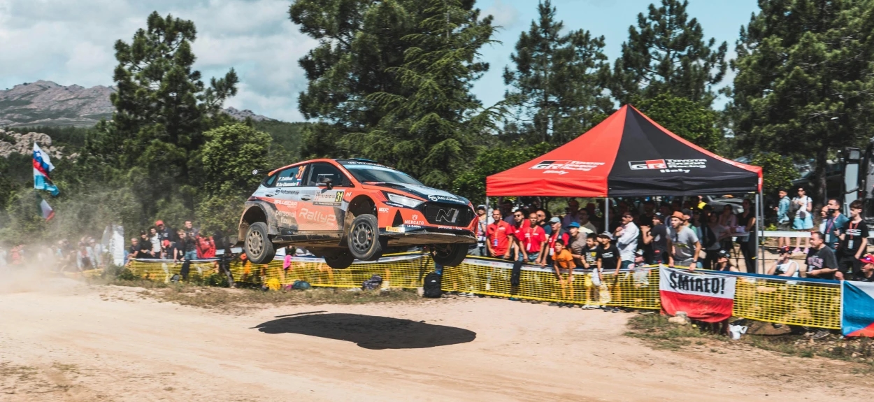 Reli automobil u vazduhu tokom skoka na šumskoj stazi, ispred publike na WRC trci