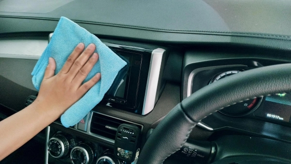 Čovek koji briše unutrašnjost svog automobila plavom krpom.