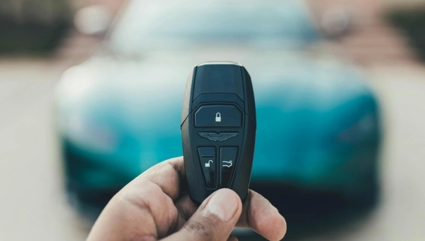 Čovek koji drži ključ od automobila sa zelenim automobilom u pozadini.