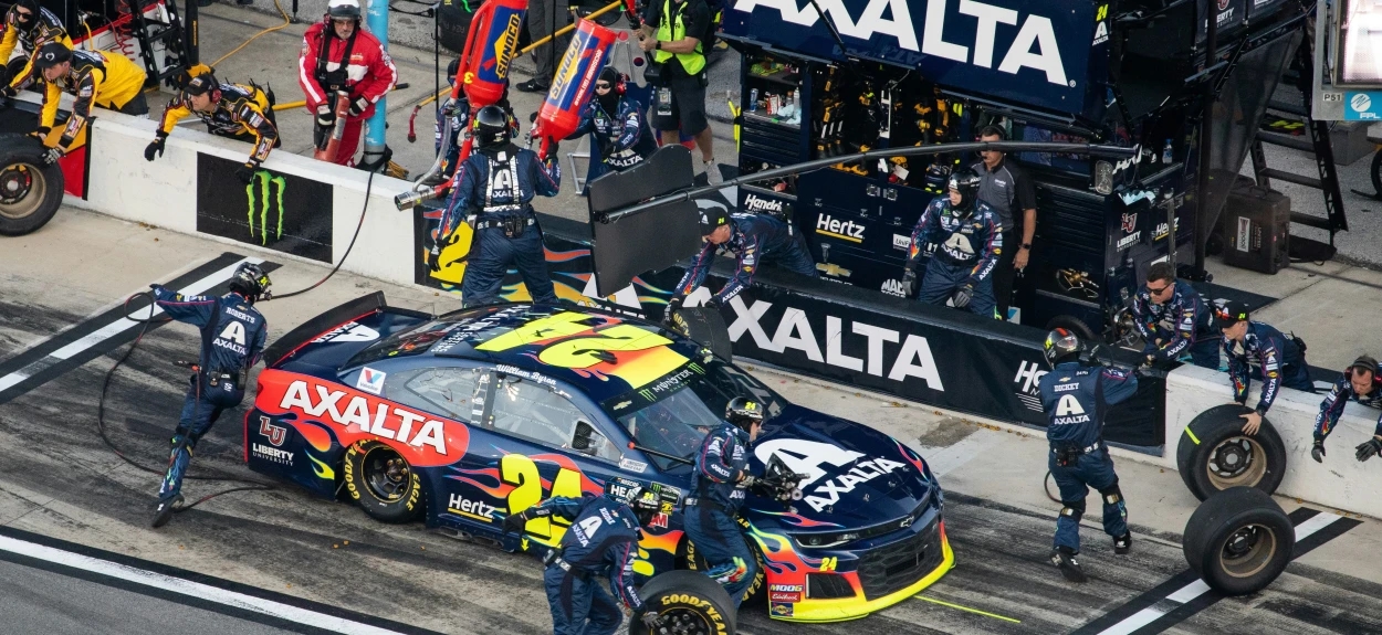 NASCAR tim menja gume i servisira automobil u boksu tokom trke, prikaz trkačke dinamike i tehnologije