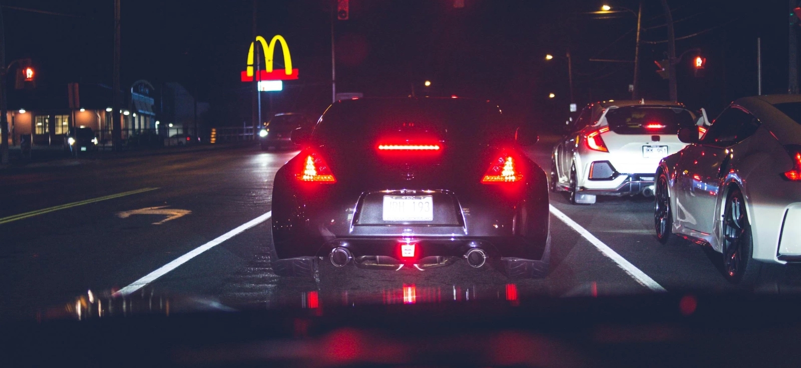 Pogled iz automobila na nocni put na semaforu.