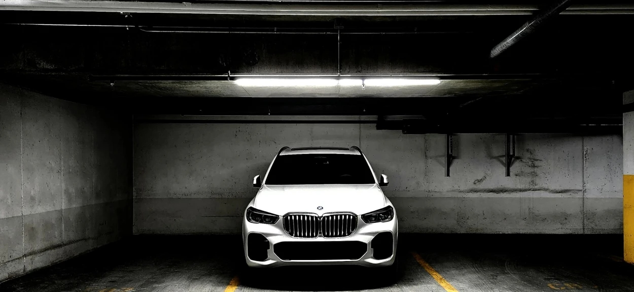 Crno vozila marke BMW parkirano u gazari sa prigušenim svetlima.