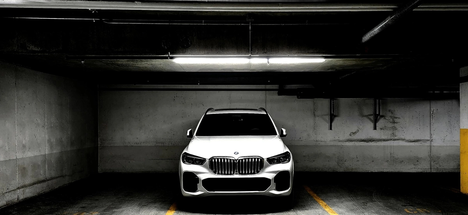 Crno vozila marke BMW parkirano u gazari sa prigušenim svetlima.