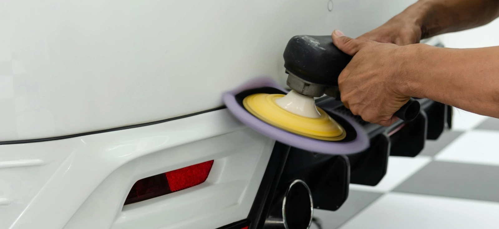 Poliranje belog automobila završni radovi na zadnjem delu vozila.