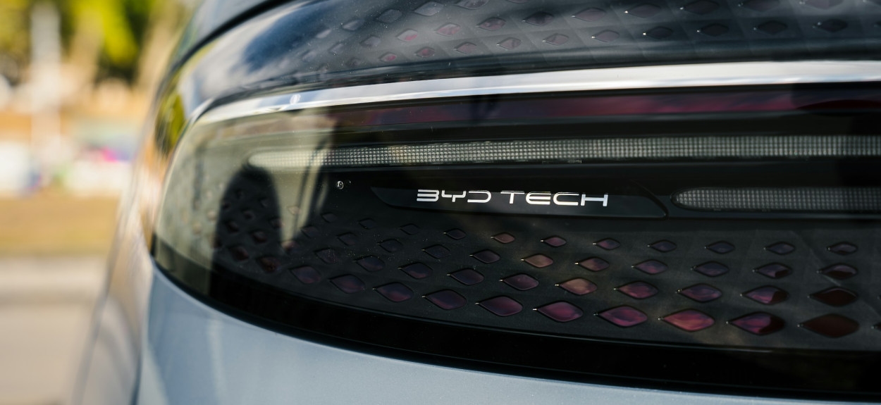 Krupni plan zadnjeg svetla BYD električnog automobila sa vidljivim natpisom BYD TECH i karakterističnom LED matricom, simbolizuje inovacije u auto-industriji