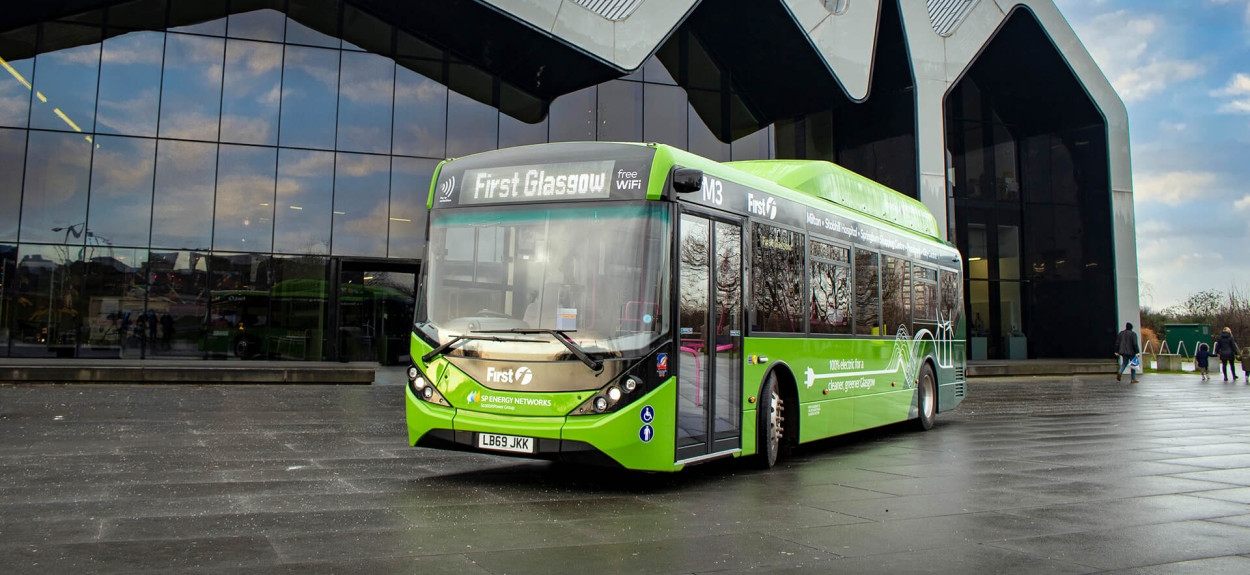 Moderni zeleni BYD električni autobus u Singapuru, u pokretu pored savremene staklene arhitekture, prikazuje globalno prisustvo kompanije u javnom prevozu