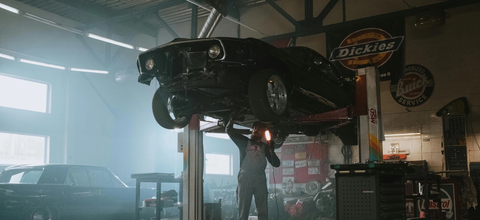 Automobil na dizalici sa mehaničarem koji gleda motor.