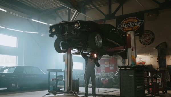 Automobil na dizalici sa mehaničarem koji gleda motor.