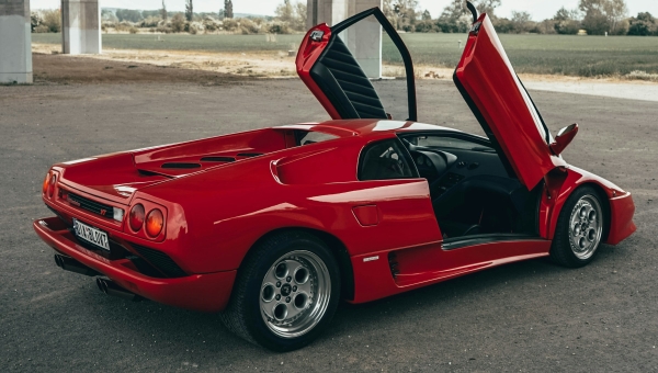 Crveni Lamborghini Diablo sa otvorenim makaze vratima ispod mosta