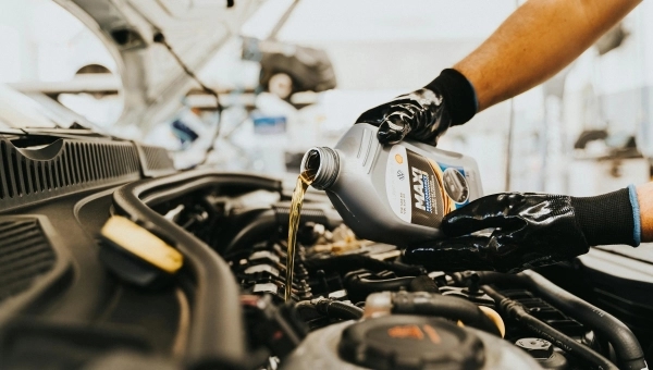 Sipanje novog motornog ulja tokom malog servisa automobila u auto servisu