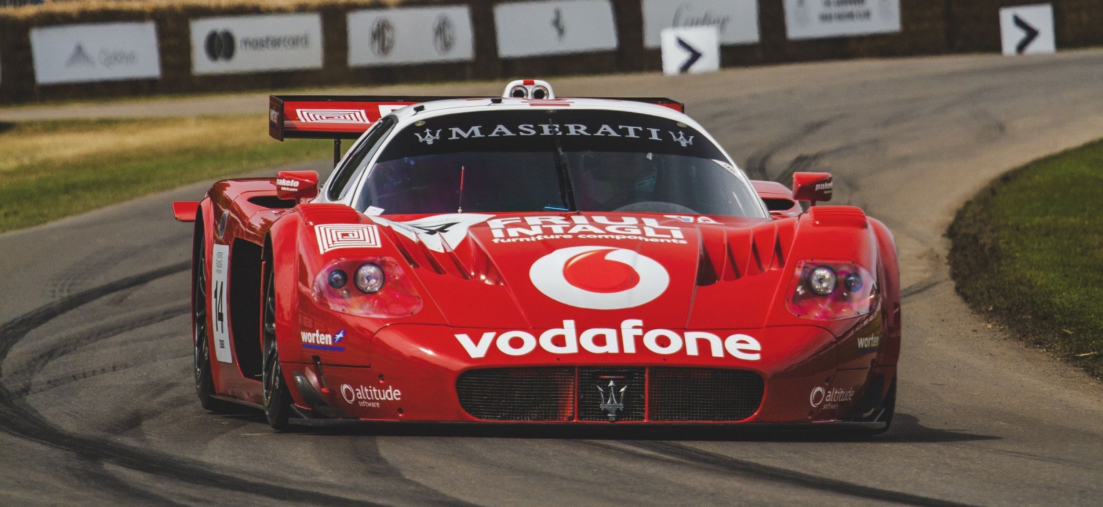 Crveni superautomobil Maserati MC12 u punoj brzini na trkačkoj stazi