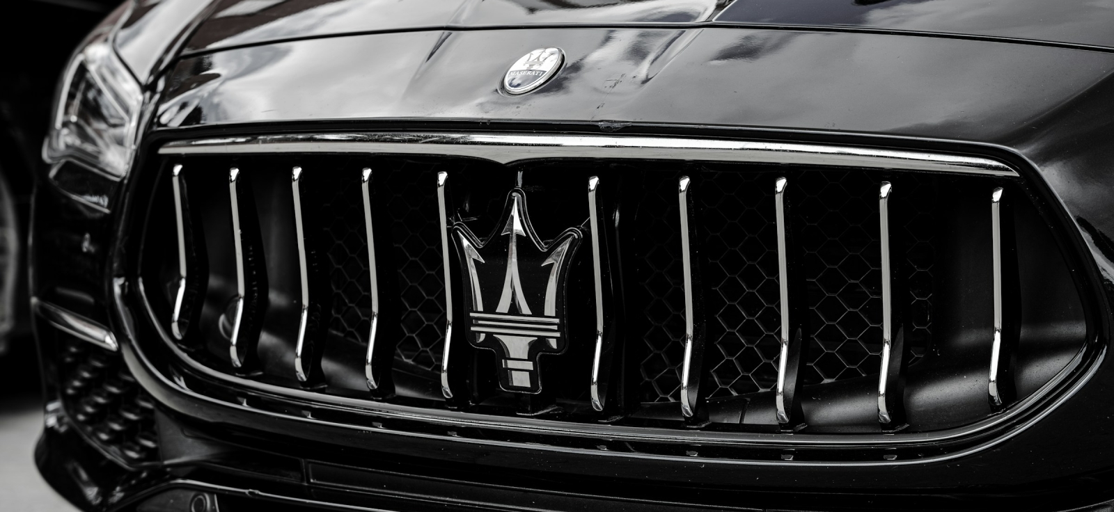 Prepoznatljivi logotip boga Neptuna i trozubac na crnoj maski Maserati modela