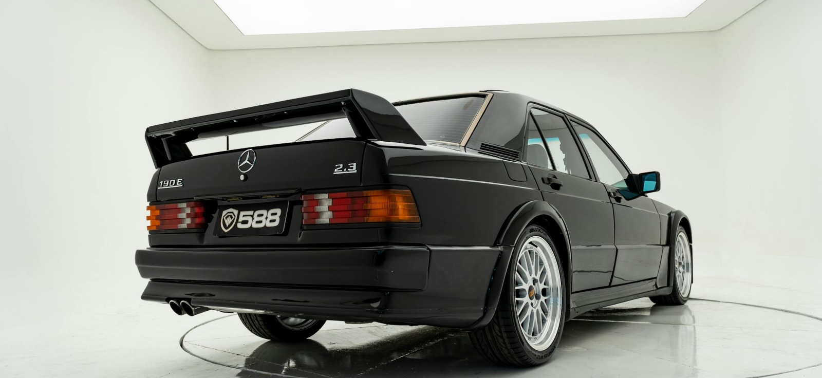 Crni Mercedes-Benz 190E 2.3-16 Cosworth sa karakterističnim zadnjim spojlerom i višestrukim aluminijumskim felnama u studiju