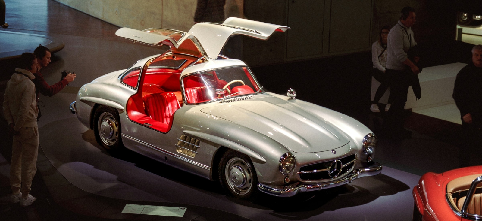 Srebrni Mercedes Benz 300SL Gullwing sa otvorenim galebovim krilima i crvenim kožnim sedištima u muzeju