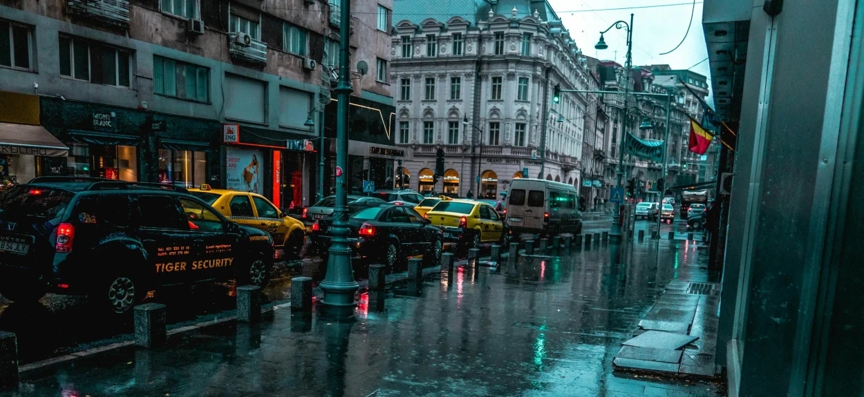 Prikaz ulice posle kiše na raskrsnici sa semaforima.