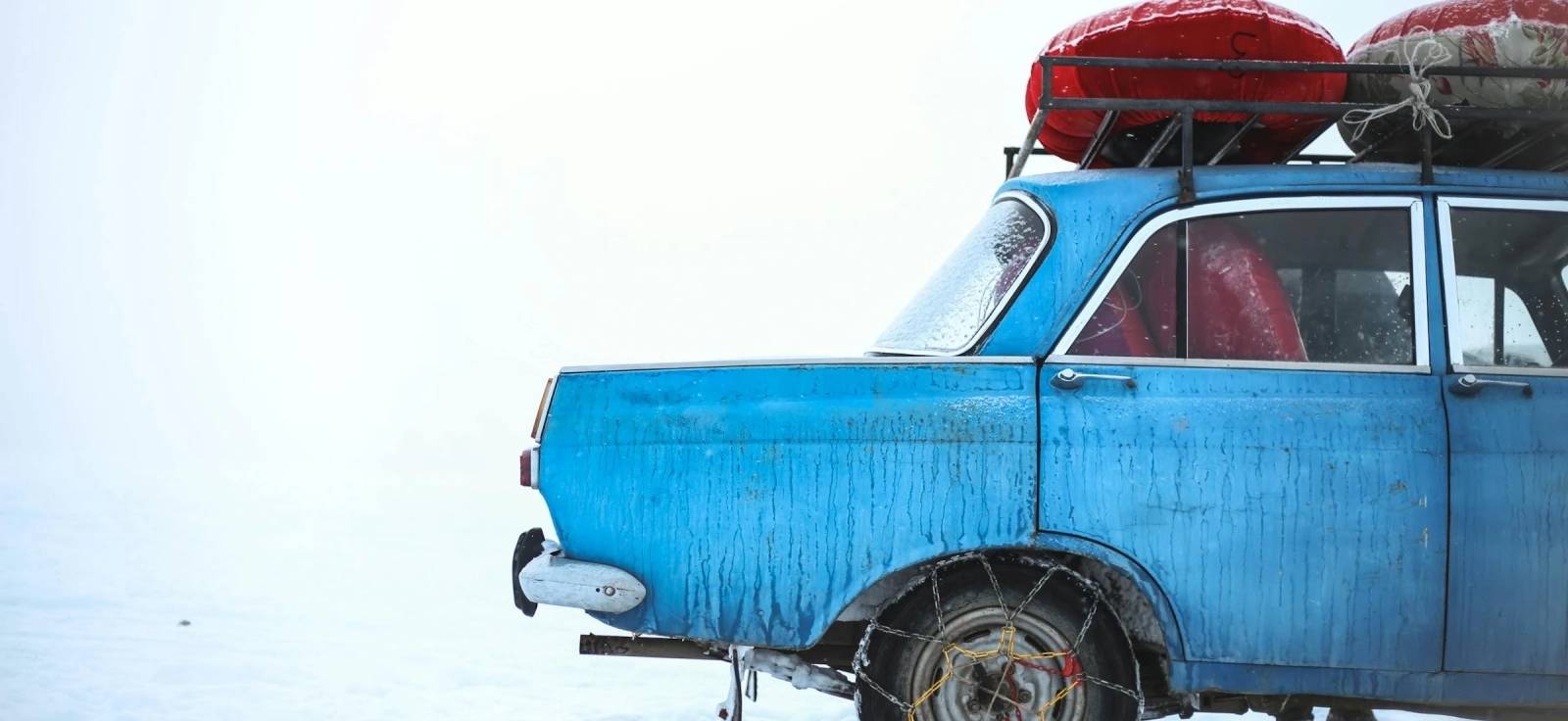 Plavi automobili u snegu sa lancima na točkovima.