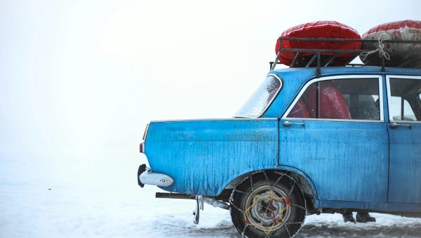Plavi automobili u snegu sa lancima na točkovima.