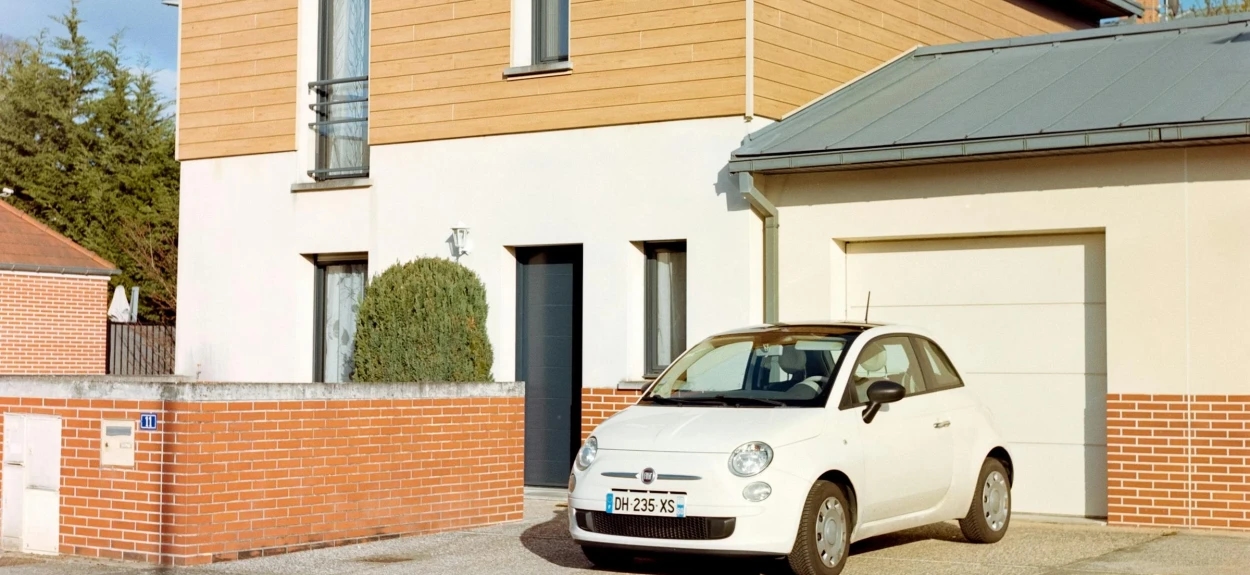 Beli auto na parkingu ispred kuće.