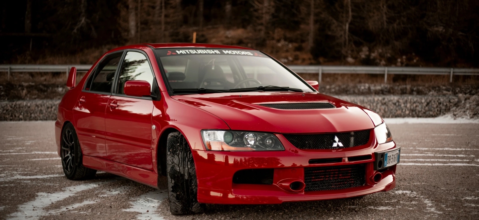 Mitsubishi Lancer Evolution IX crveni sportski automobil parkiran na asfaltu