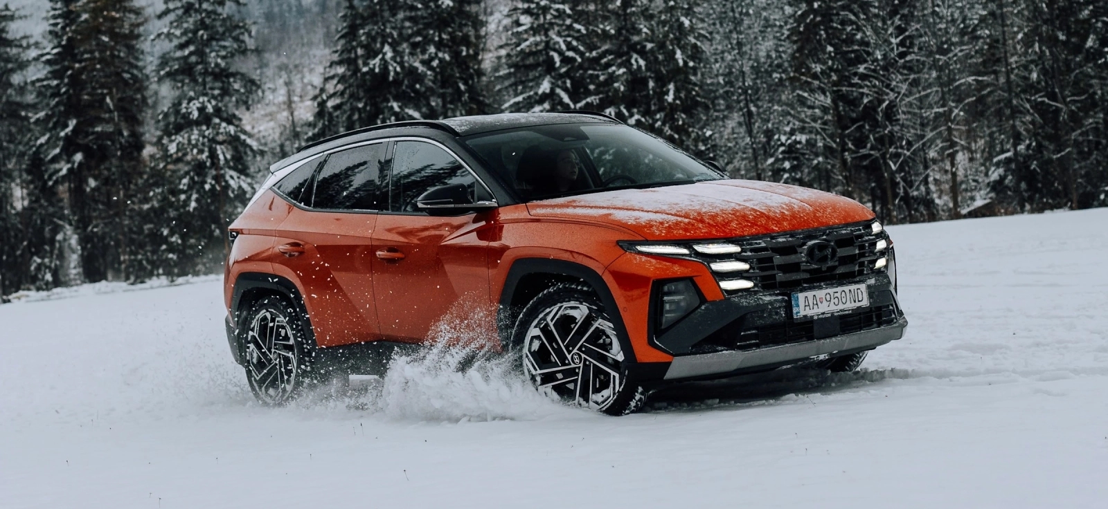 Narandžasti Hyundai Tucson četvrte generacije u vožnji po snegu – idealan SUV za zimske uslove u Srbiji