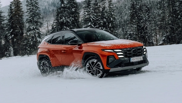 Narandžasti Hyundai Tucson četvrte generacije u vožnji po snegu – idealan SUV za zimske uslove u Srbiji