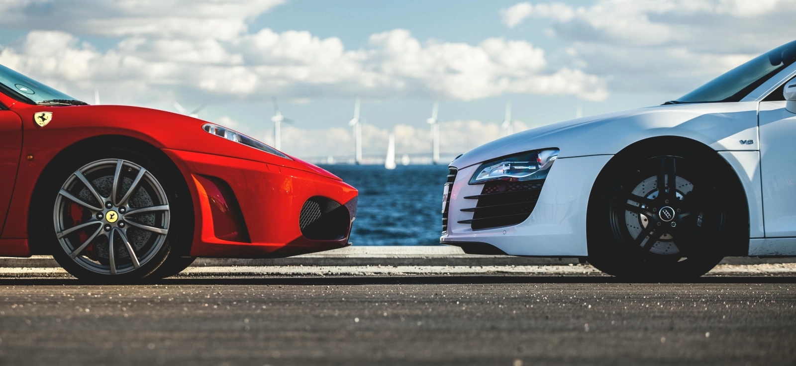 Crveni Ferrari i beli sportski automobil naspram jedan drugog na stazi kao simbol auto-rivalstva