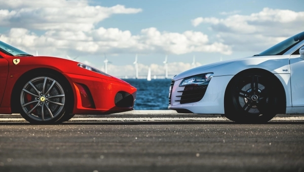 Crveni Ferrari i beli sportski automobil naspram jedan drugog na stazi kao simbol auto-rivalstva