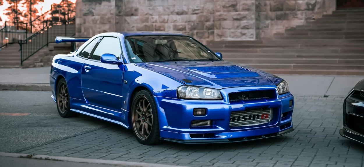 Nissan Skyline GT R R34 V Spec verzija parkirana ispred zgrade, kultni japanski sportski automobil
